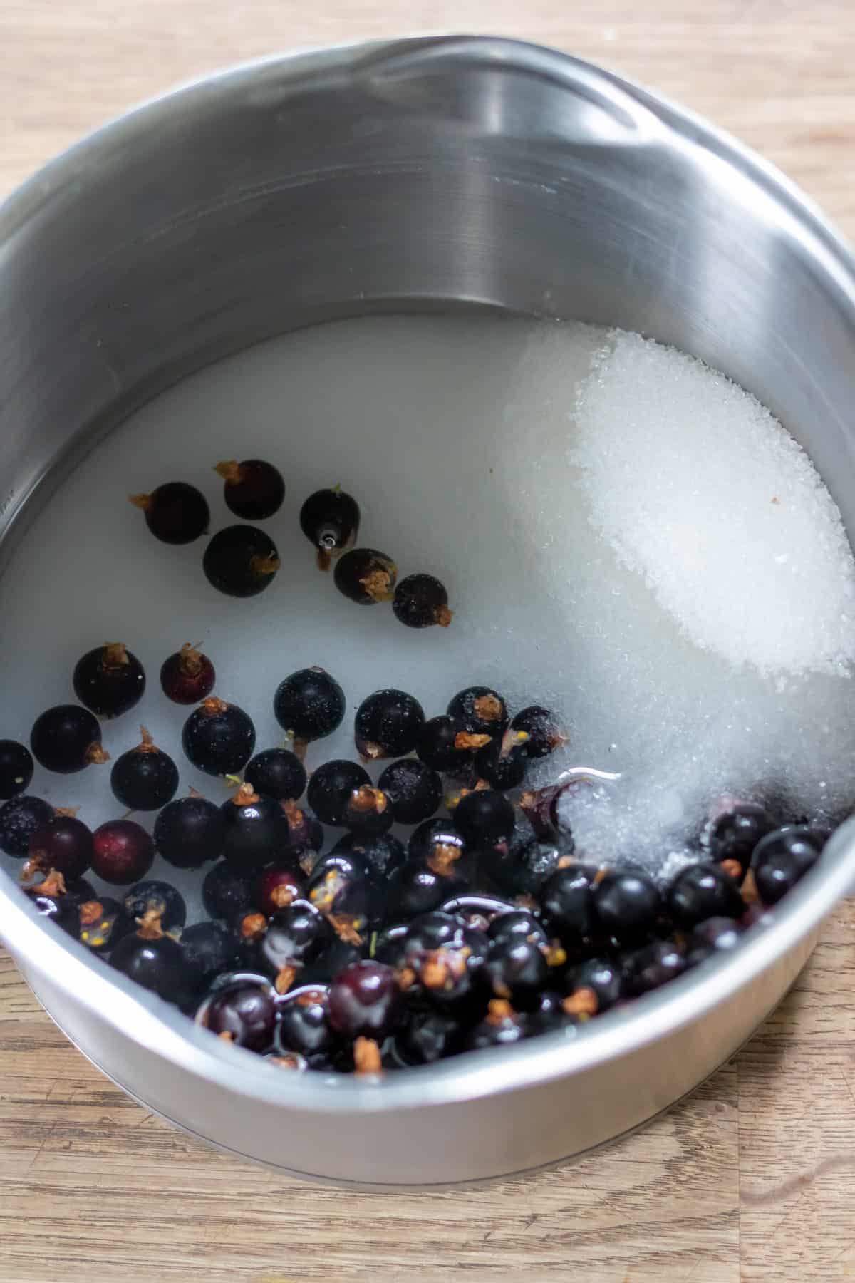 Pot of water, sugar and blackcurrants.