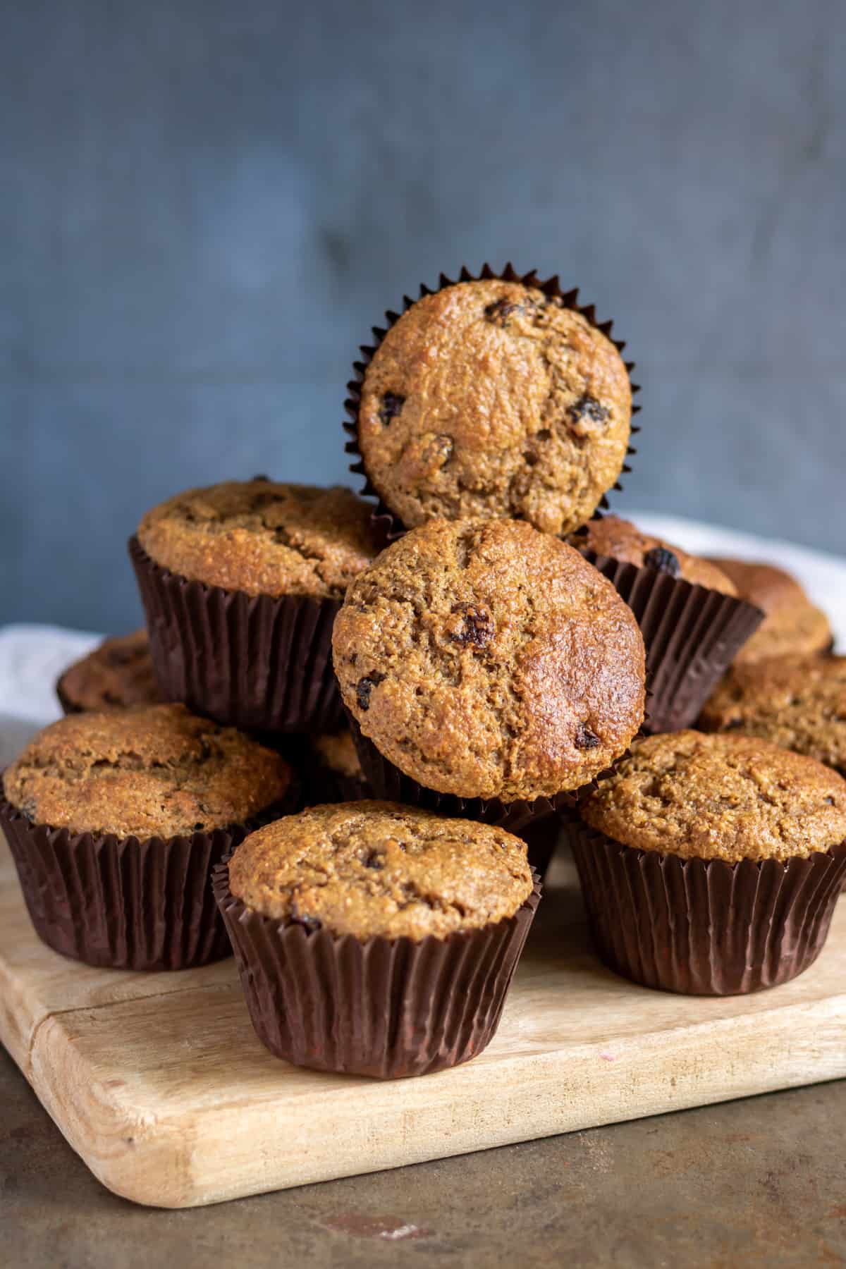 A pile of raisin bran muffins on a wooden board.