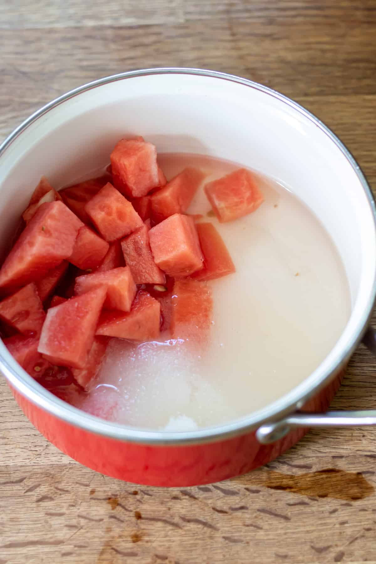 Cubes of watermelon in a pot with sugar and water.