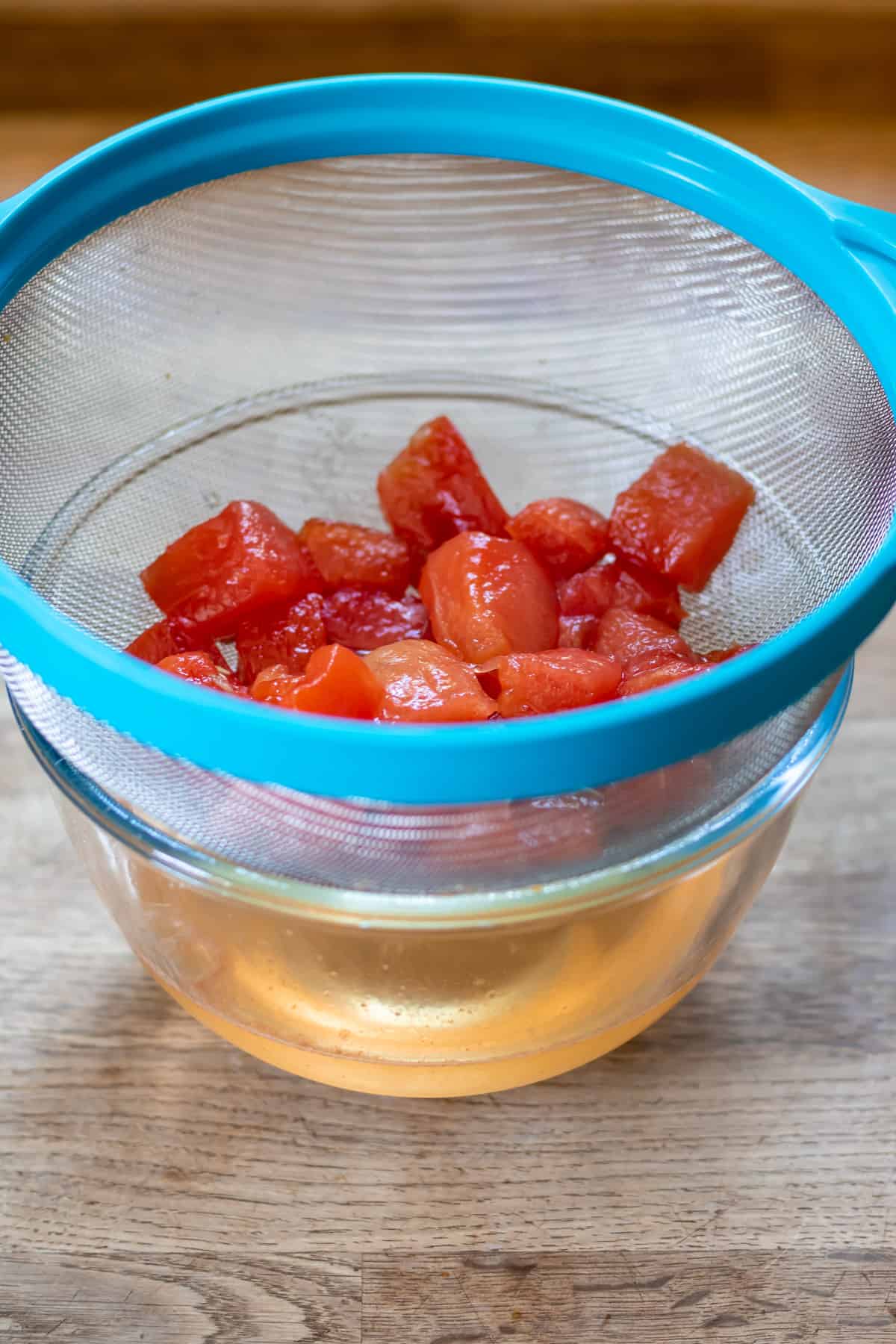 Straining the watermelon out of the simple syrup through a seive.