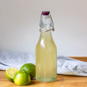 Bottle of lime juice on a table.