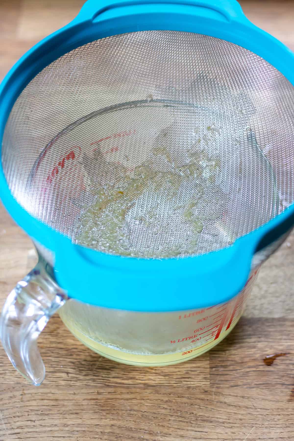 Straining lime syrup into a dish.