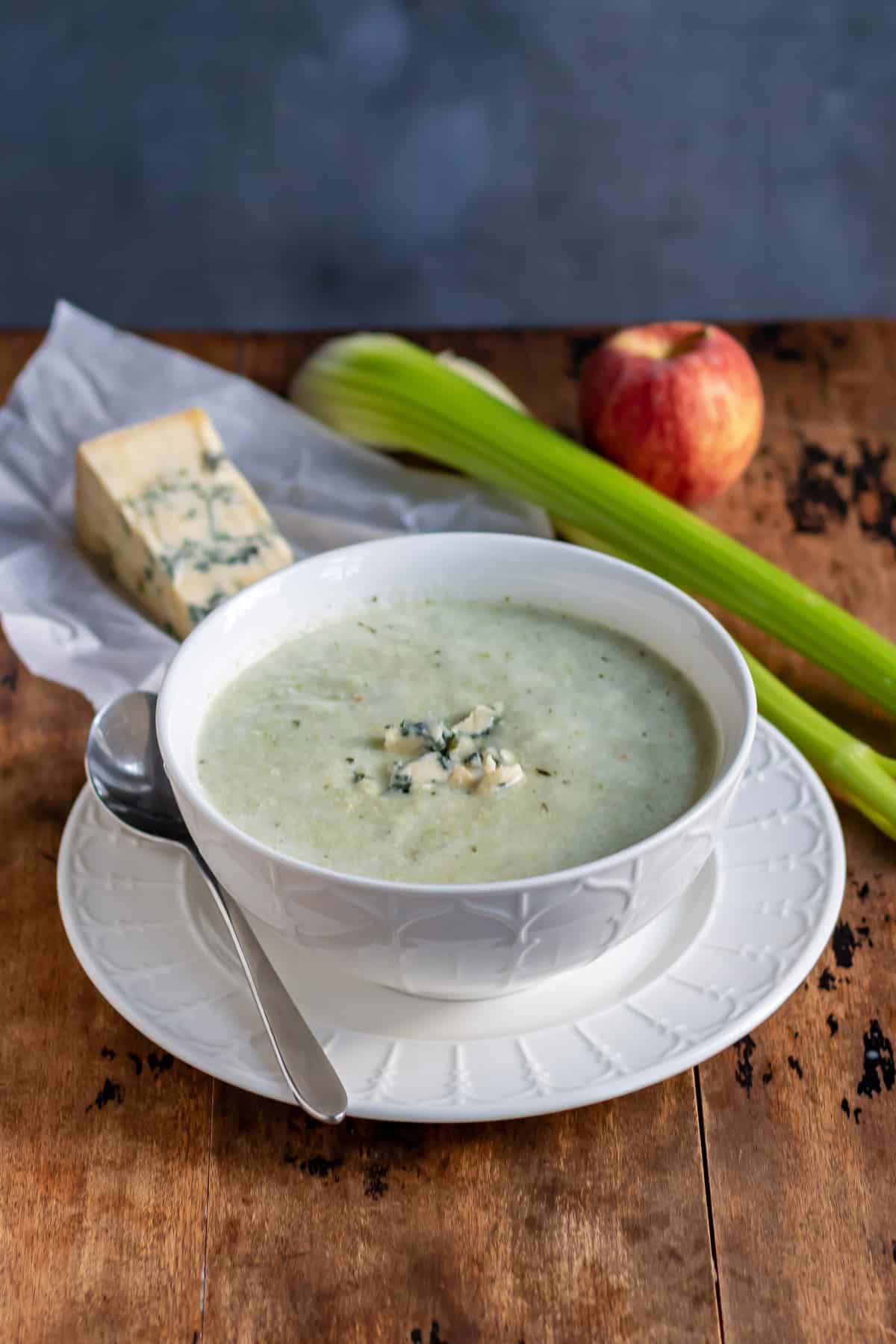 Table with soup, blue cheese, celery and apple.