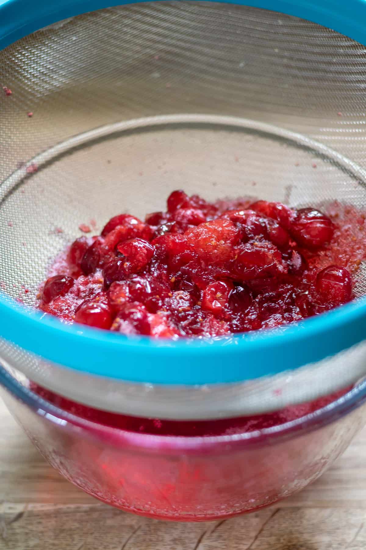 Straining the cranberries out of the cranberry syrup.