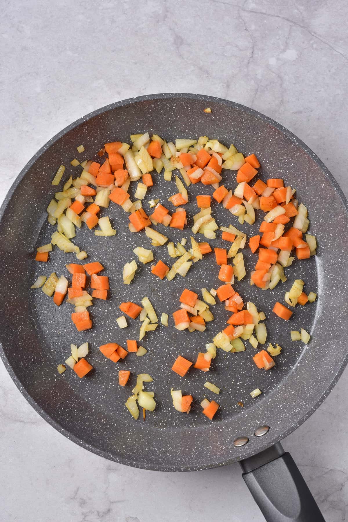 Cooking onion, carrot and garlic in a pan.