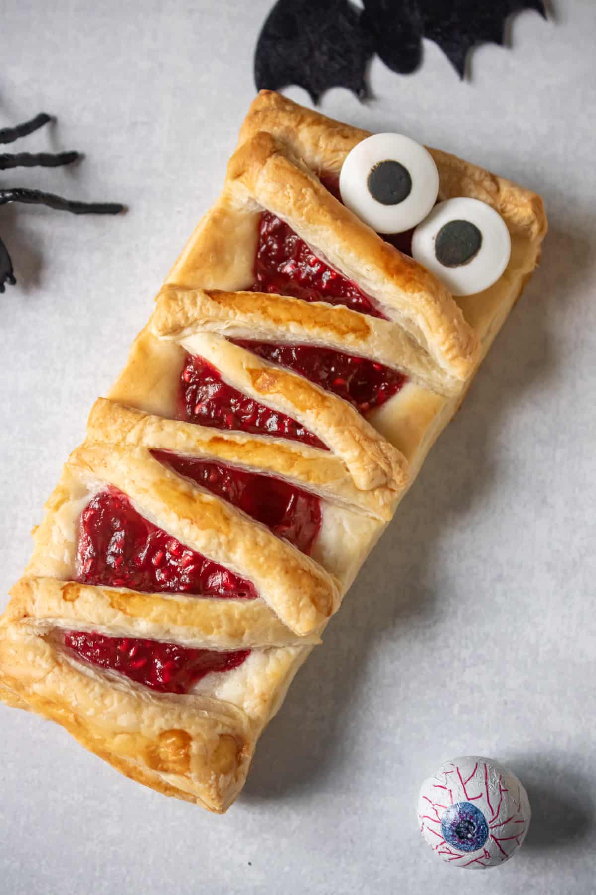 Close up of a hand pie shaped like a halloween mummy, with candy eyes.