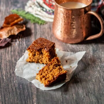 Wooden table with a mug and a piece of Yorkshire Parkin Cake.