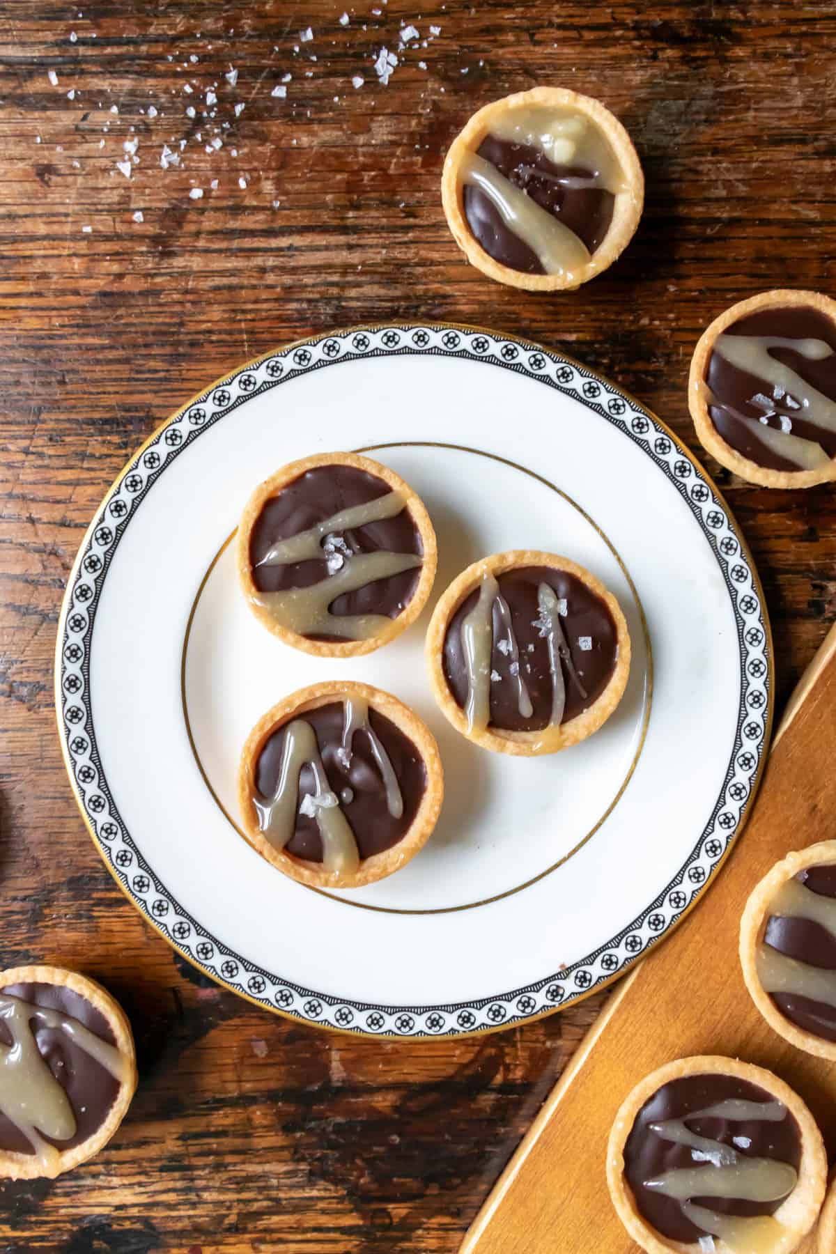 Wooden table with a plate of mini dark chocolate tarts.