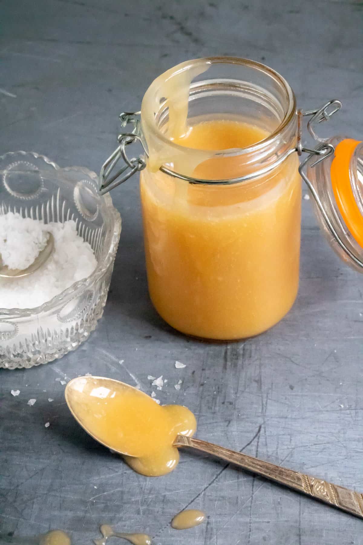 Spoonful of salted caramel sauce on a table in front of a jar of it.