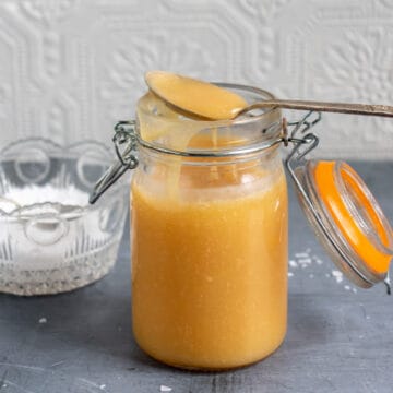 Jar of salted caramel sauce with a spoon of it resting on top.