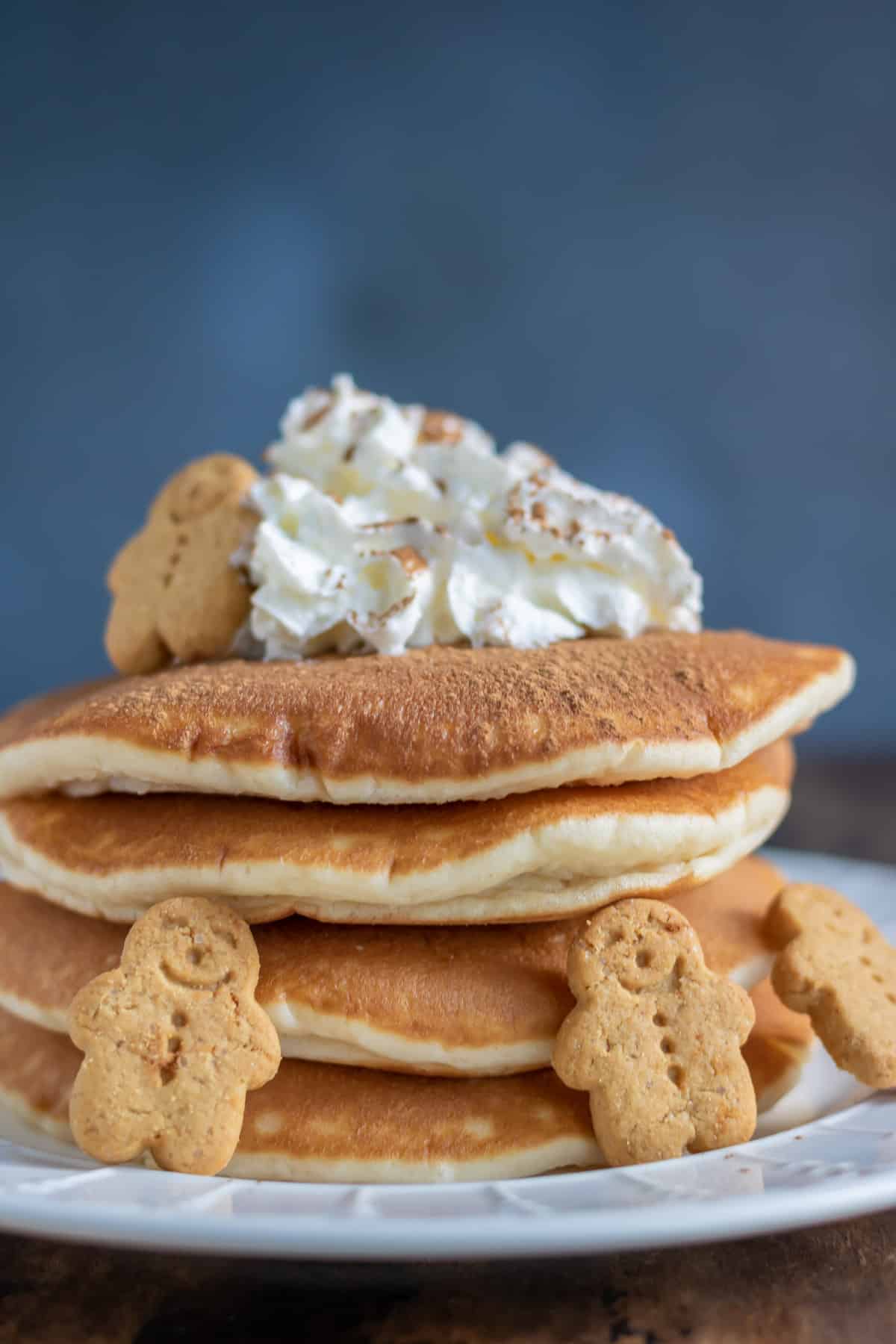 Close up of plate of gingerbread pancakes topped with whipped cream, spices and gingerbread men.