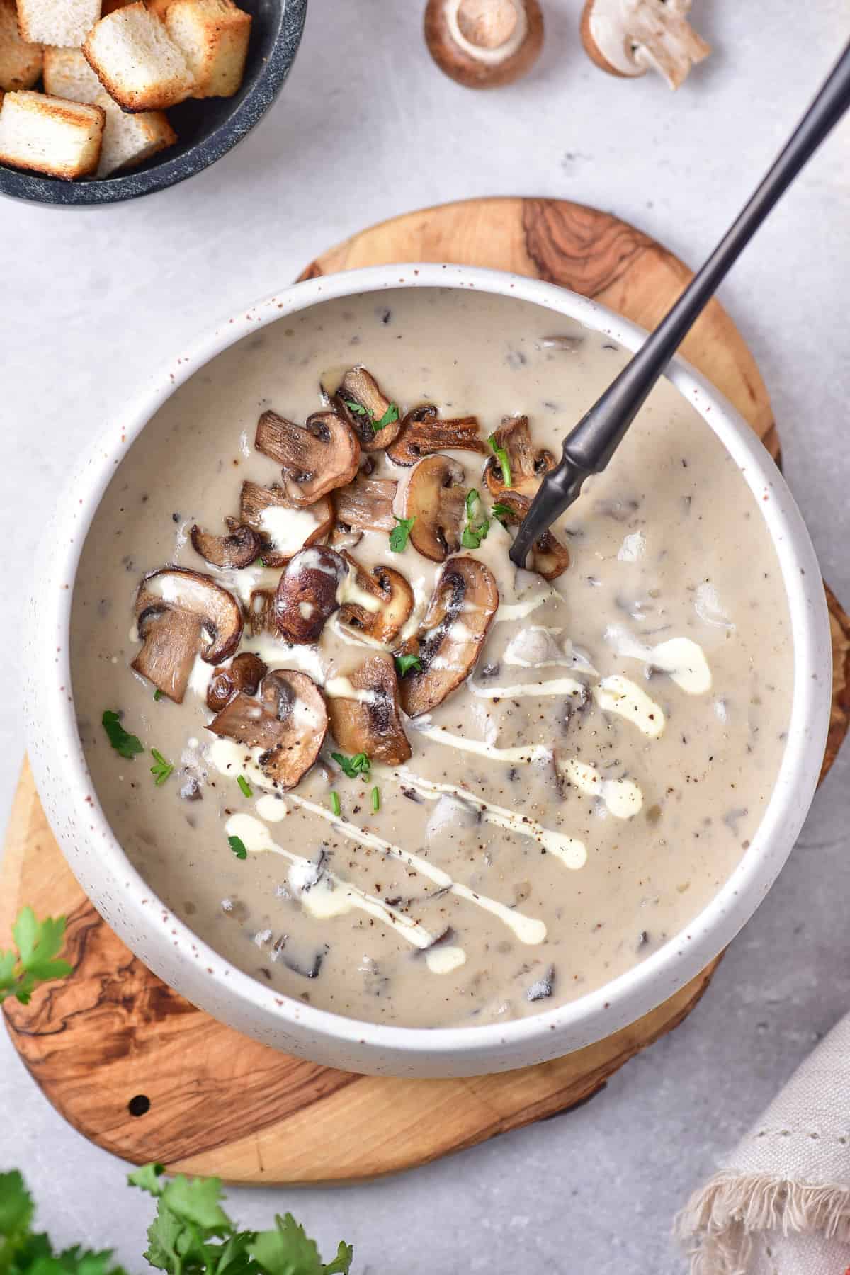 Table with a bowl of mushroom soup with a spoon in it.