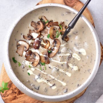 Bowl of creamy mushroom soup, topped with fried mushrooms.
