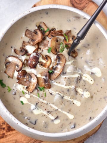 Bowl of creamy mushroom soup, topped with fried mushrooms.