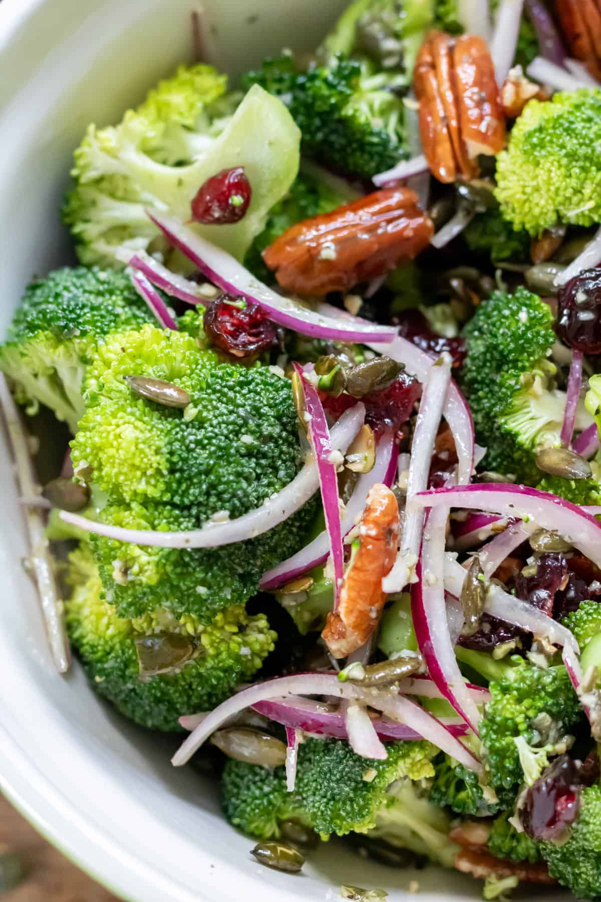 Close up of Broccoli cranberry salad in a bowl, with maple pumpkin seed dressing.