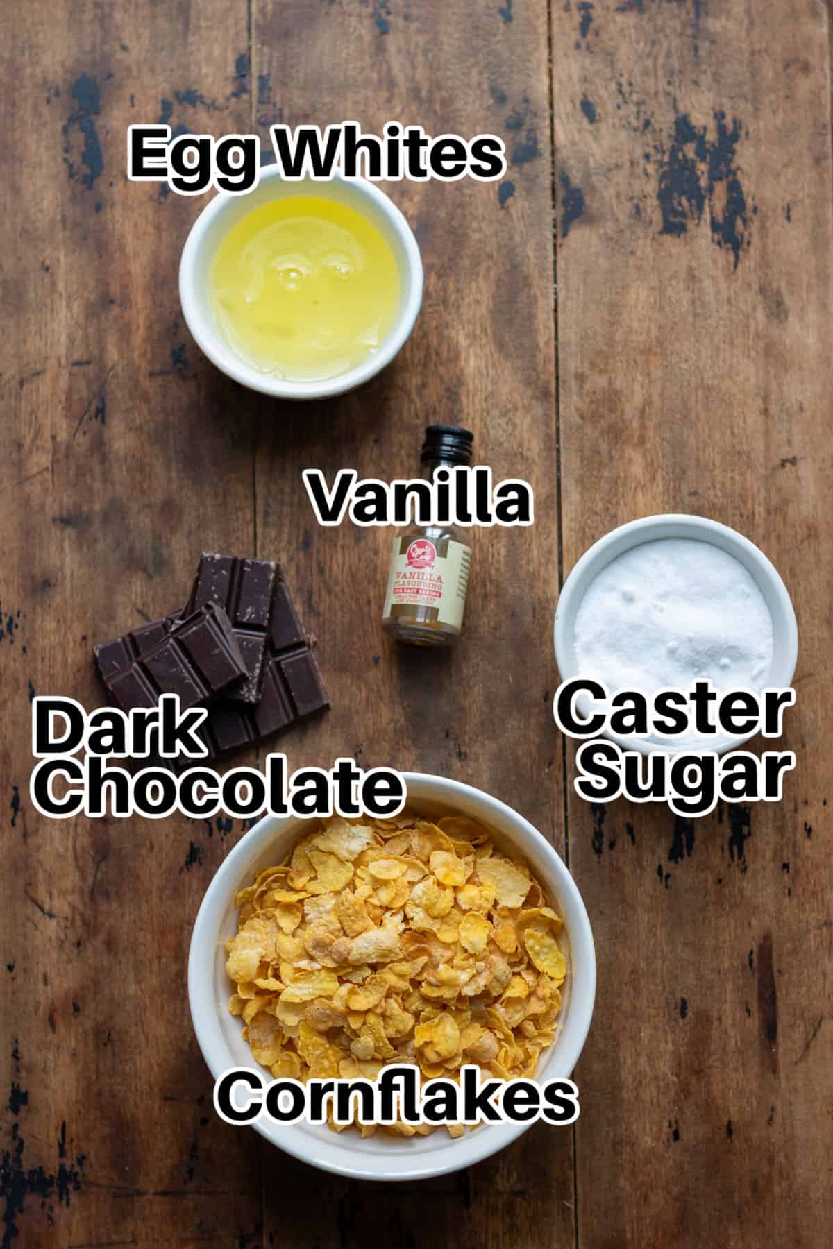 Egg whites, sugar, vanilla, chocolate and cornflakes on a table.