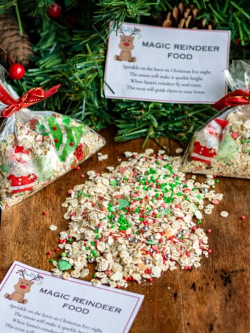 Wooden table with a pile of magic reindeer food, bags of it, and printable poem tags.