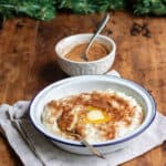 Wooden table, Christmas garland, and a bowl of risengrod - Danish rice porridge, with cinnamon sugar and butter.