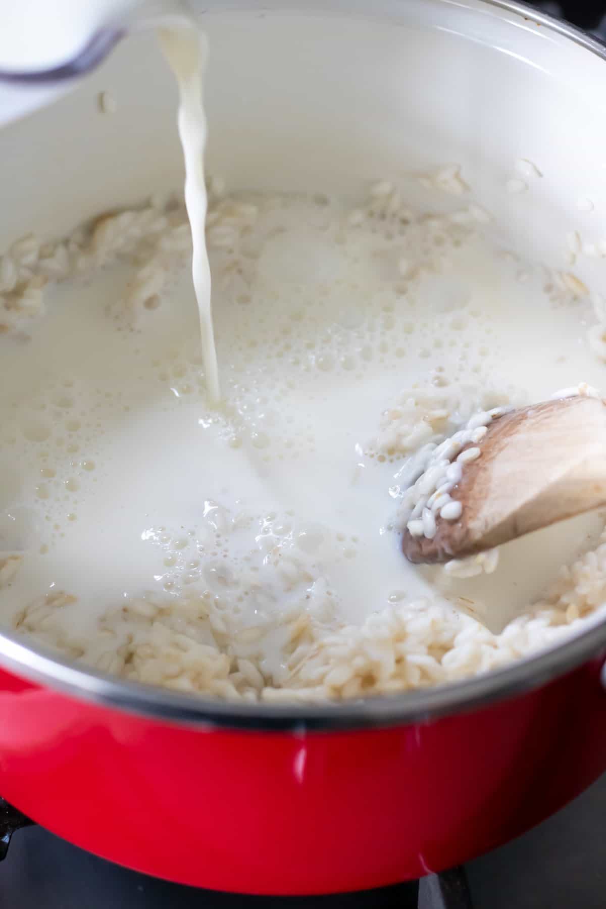 Adding milk to the pot of rice.