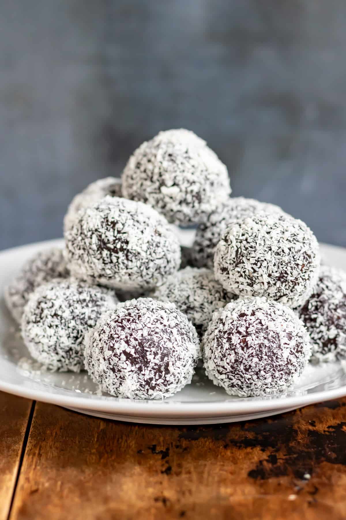 Side view of romkugler Danish rum balls in coconut, piled onto a plate.