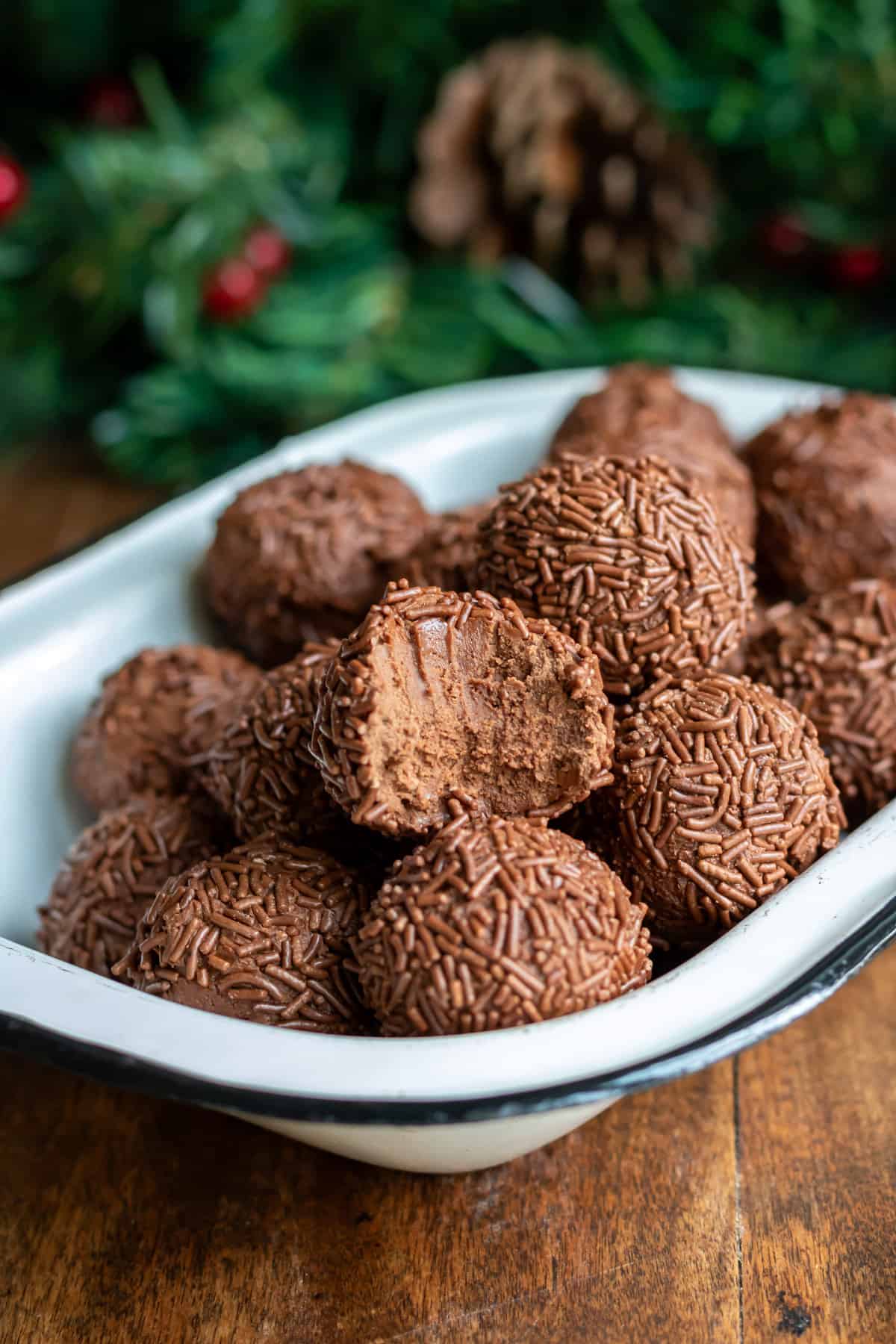 Rum ball with a bite out, in a dish of other rumkugeln.
