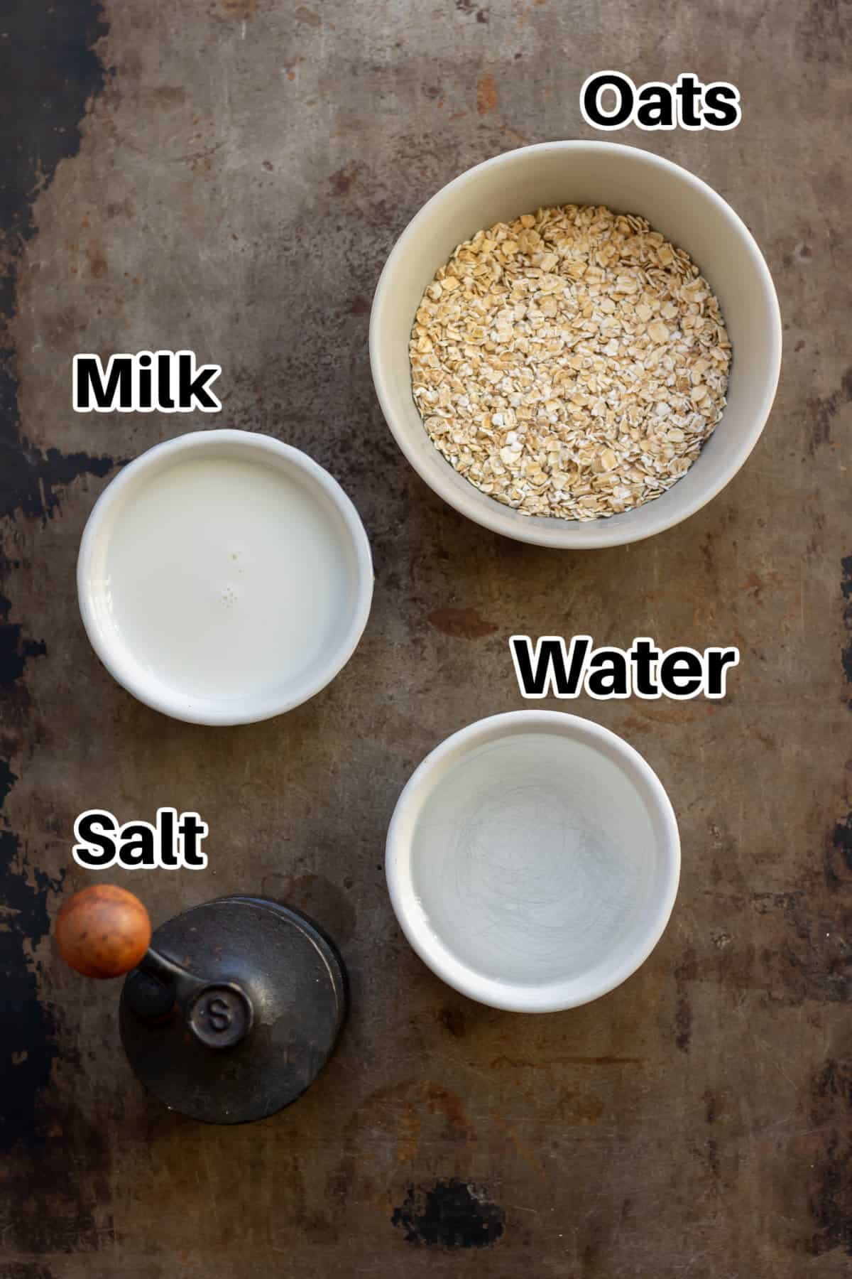 Metal table with bowls of oats, milk, water and a salt mill.