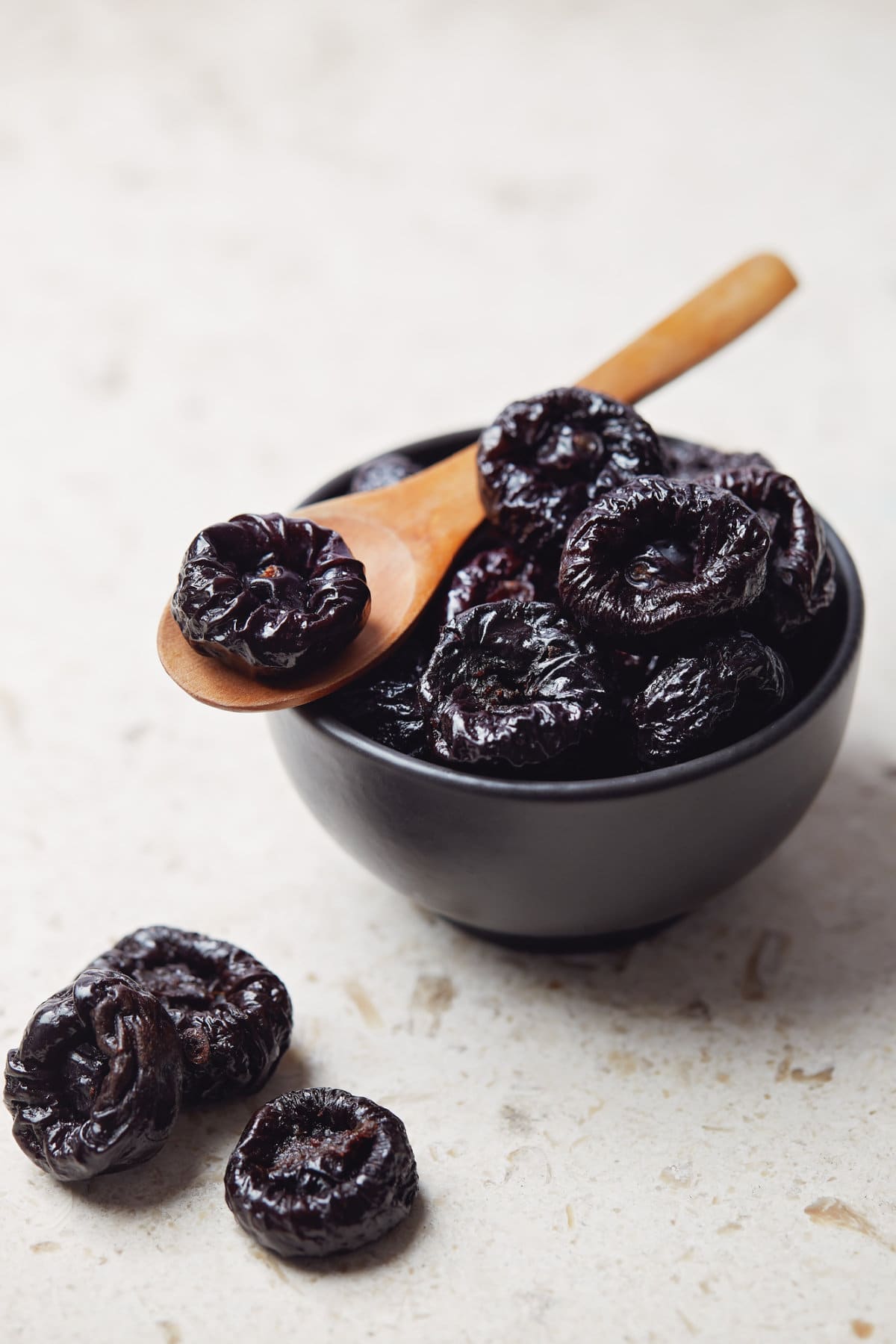 Bowl of prunes, with a wooden spoon with a prune in it.