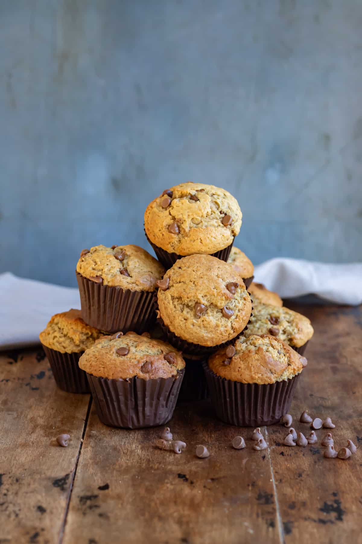 Pile of chocolate chip peanut butter muffins on a wooden table.