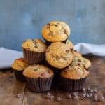 Pile of chocolate chip peanut butter muffins on a wooden table.