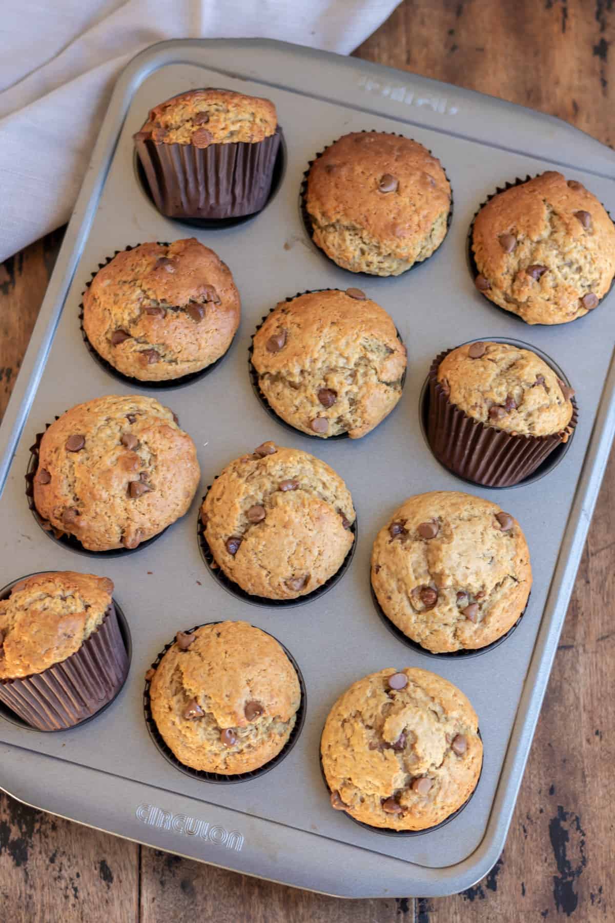 Baked chocolate chip peanut butter muffins cooling in a pan.