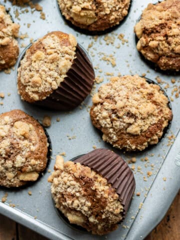 Close up of baked streusel-topped cinnamon muffins in a muffin pan.
