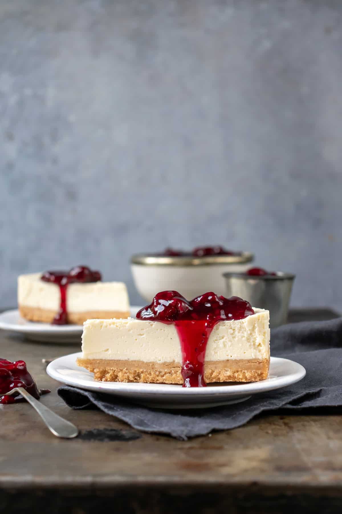 Side view of a slice of vegan cheesecake with berry sauce.