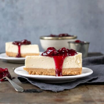 Side view of a slice of vegan cheesecake with berry sauce.