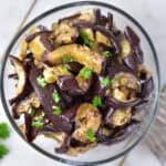 Looking down at a side dish in a bowl - with roasted aubergine (eggplant) in a honey garlic sauce.