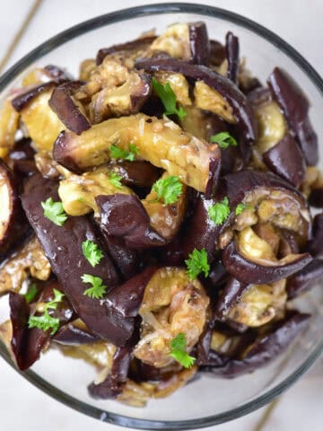 Looking down at a side dish in a bowl - with roasted aubergine (eggplant) in a honey garlic sauce.