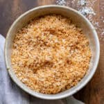 Bowl of toasted shredded coconut on a wooden table.