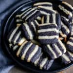 Close up of a plate piled with black and white striped Beetlejuice cookies.