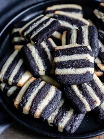 Close up of a plate piled with black and white striped Beetlejuice cookies.