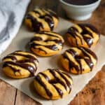 Baked pumpkin donuts with chocolate glaze on baking paper on a table.