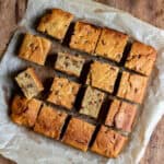 Wooden table with chocolate chip butternut squash cake cut into squares on parchment paper.
