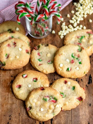 A pile of white chocolate candy cane cookies on a wooden table.