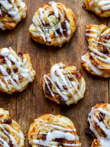 Wooden table with lots of mincemeat puff pastry swirls.