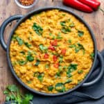 Wooden table with a serving dish of cauliflower and lentil curry.