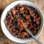 Looking down at a spoon in a dish of raisin compote.