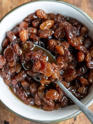 Looking down at a spoon in a dish of raisin compote.