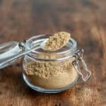 A spoon resting on a small jar of yemeni sweet hawaij spice mix.