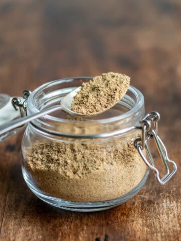 A spoon resting on a small jar of yemeni sweet hawaij spice mix.