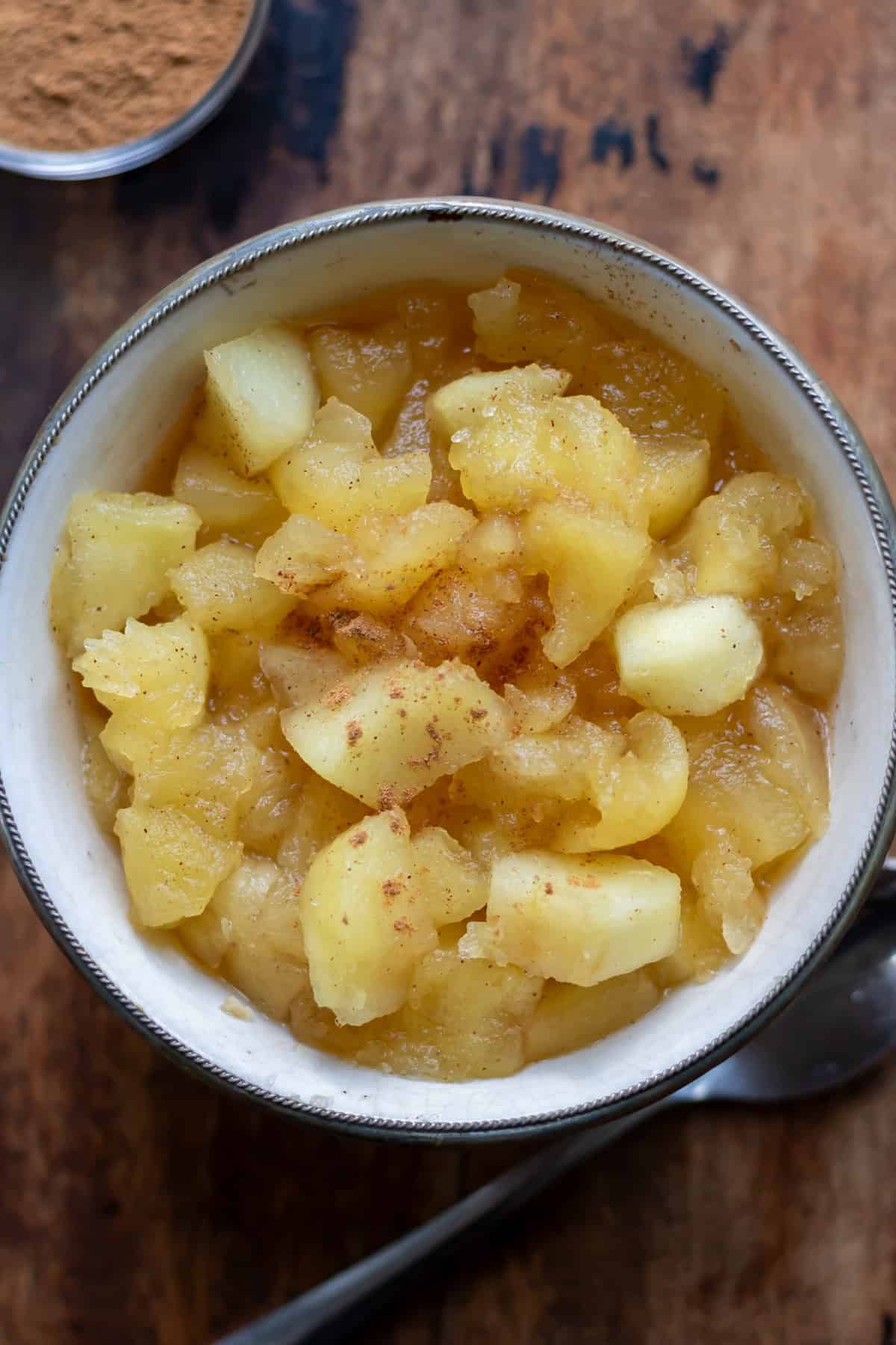 Close up of a dish of apple compote with cinnamon on top.