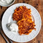 Close up of two sweet potato fritters on a plate on a wooden table.