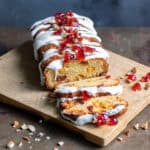 A cherry marzipan cake on a wooden board, with two slices cut next to it.